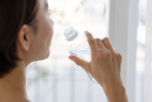 ペットボトルの水を飲む女性