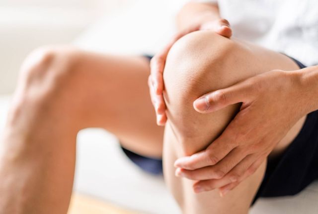 痛めた膝を手で触っている男性
